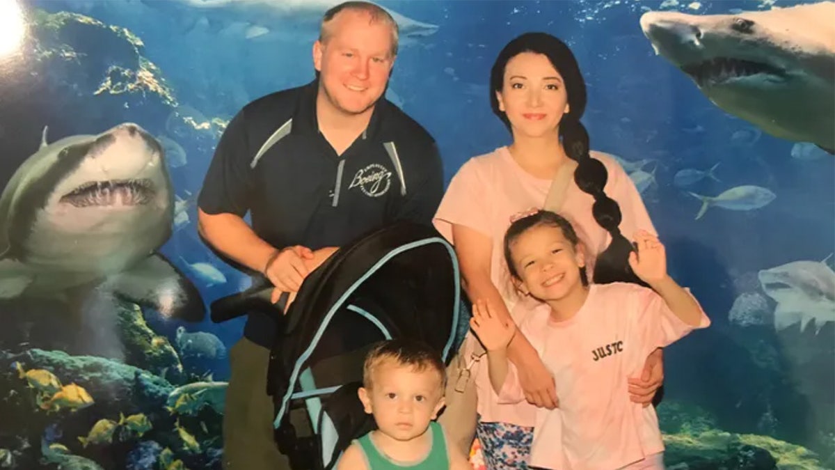 Una familia de cuatro miembros se encuentra frente a un mural de tiburones.