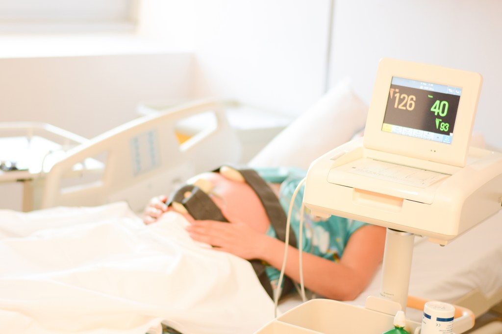 Mujer embarazada recibiendo monitorización cardíaca prenatal en la cama de un hospital
