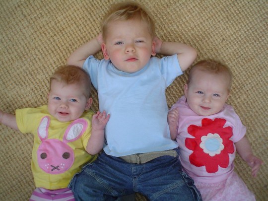 Josh y sus hermanos, los gemelos, tumbados en el suelo sonriendo.