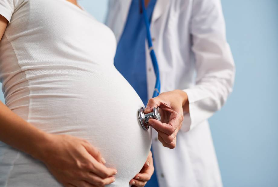 El médico escucha el ritmo cardíaco del bebé en el vientre de una mujer embarazada