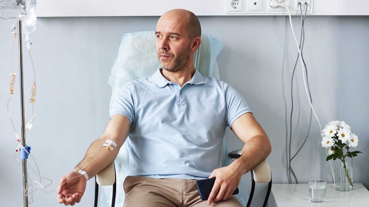 Hombre con goteo intravenoso mientras está sentado en una silla cómoda