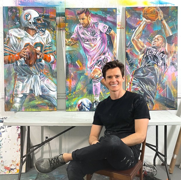 El artista Kyle Lucks se sienta frente a un tríptico de Dan Marino, Lionel Messi y Dwyane Wade en su estudio de West Palm Beach.