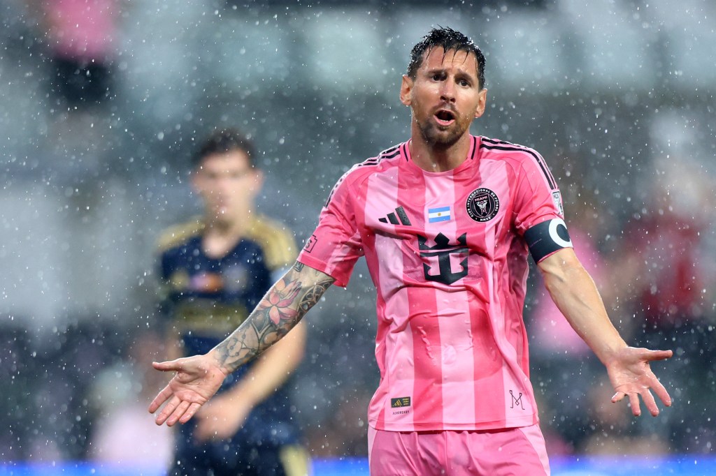 Lionel Messi reacciona durante un partido de fútbol bajo la lluvia vistiendo una camiseta rosa del Inter Miami CF.