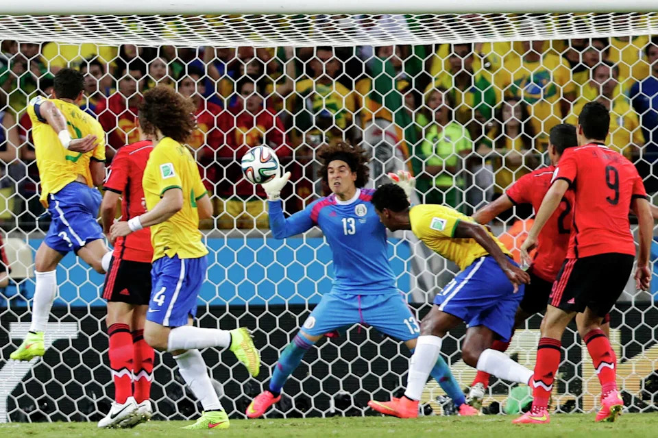 El portero mexicano Guillermo Ochoa (13) salva el balón después de un cabezazo del brasileño Fred (i) durante un partido de fútbol del Grupo A de la Copa Mundial entre Brasil y México en el estadio Castelao de Fortaleza, Brasil, el martes 17 de junio de 2014. (Marcio José Sánchez/AP)