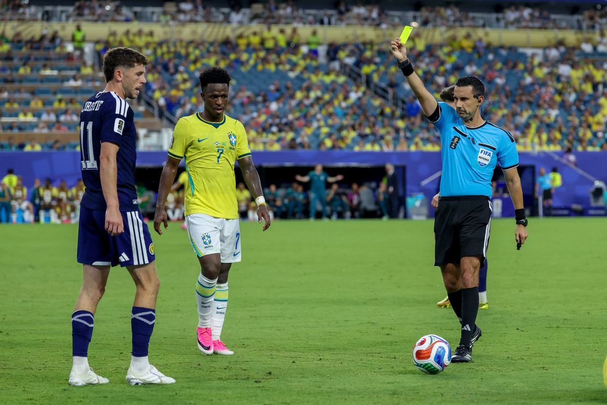 César Lamo muestra tarjeta amarilla a Ryan Christie durante la victoria de Brasil sobre Escocia en el Mundial