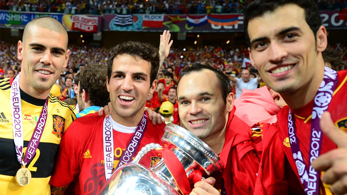 El portero español Víctor Valdés y los centrocampistas Cesc Fábregas, Andrés Iniesta y Sergio Busquets posan con el trofeo de la Eurocopa 2012.