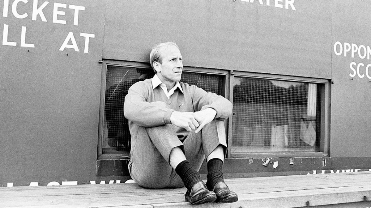 El futbolista inglés Bobby Charlton juega al cricket sentado en la parte inferior del marcador.